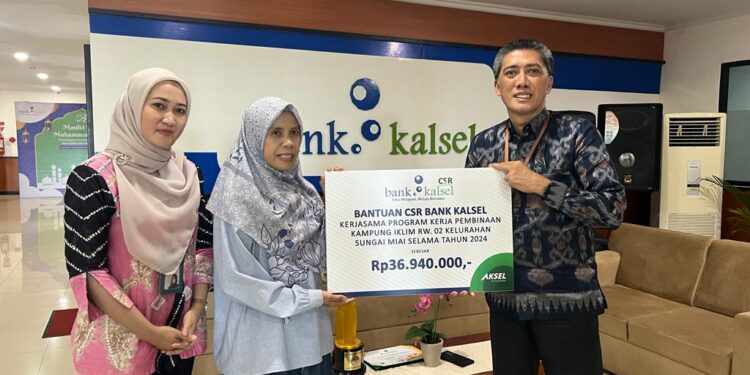 DIREKTUR Utama Bank Kalsel Fahrudin saat menyerahkan bantuan untuk mendukung program pembinaan kepada Agusliana Ketua Kampung Iklim RW 02 Kelurahan Sungai Miai.