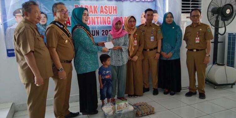 BAPAK ASUH-PJ Bupati Tapin M Syarifuddin MPd bersama ketua TP PKK Masrupah dan didampingi Asisten Ekobang H Errani Martin dan Staf Ahli Ekobang H Syafrudin SIP bersama Camat Lokpaikat Arie Wijaya sata menyerahkan bantuan bapak asuh anak stunting pada kunjungan Mojang Bastari di Kecamatan Lokpaikat, Selasa (09/01).
