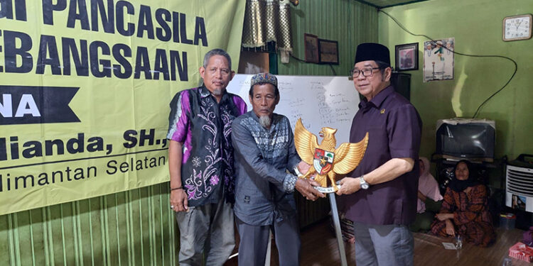 ANGGOTA DPRD Kalsel Dr H Karlie Hanafi Kalianda SH MH saat menyerahkan cinderamata berupa lambang negara saat sosialisasi di Kelurahan Ulu Benteng, Kecamatan Marabahan, Kabupaten Batola.