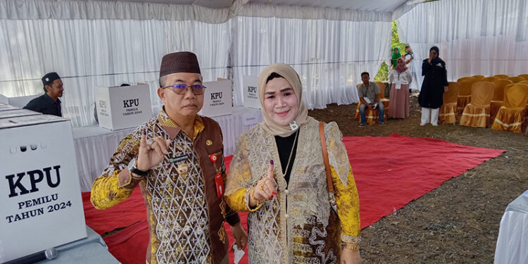 PJ Bupati Tapin M Syarifuddin MPd bersama istri saat usai mencoblos di TPS 11 dan memperlihatkan tanda tinta, Rabu (14/2).