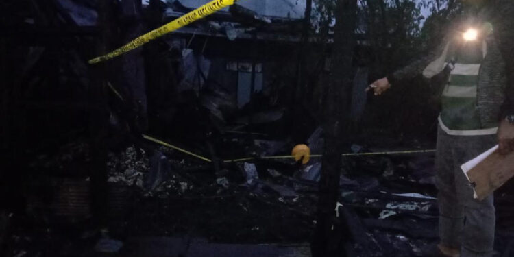 PETUGAS kepolisian saat memasang garis polisi di titik pertama api muncul.