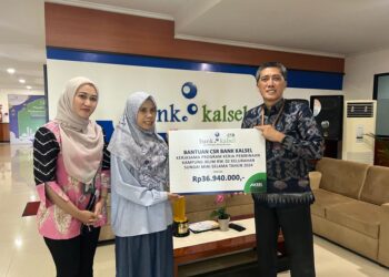 DIREKTUR Utama Bank Kalsel Fahrudin saat menyerahkan bantuan untuk mendukung program pembinaan kepada Agusliana Ketua Kampung Iklim RW 02 Kelurahan Sungai Miai.