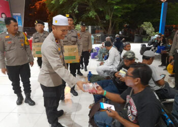 BAGIKAN SNACK - Kapolsek KPL Kompol Boma Wedhayanto Purnomo dan Kapolsek Banjarmasin Barat Kompol Aris Munandar saat membagikan snack dan nasi ke jemaah Haul Abah Guru Sekumpul selaku penumpang kapal laut di ruang tunggu penumpang Pelabuhan Trisakti Banjarmasin, Senin (15/1) malam.