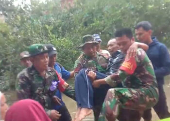BABINSA saat menggendong seorang warga yang tengah sakit untuk pulang ke rumahnya, Selasa (16/1).