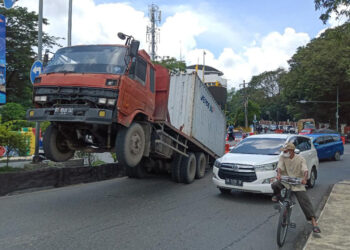 TERJUNGKIT - Sebuah mobil kontiner terjungkit di oprit Jembatan Merdeka, Senin (26/2) sekitar pukul 11.00 Wita. Kecelakaan tunggal itu pun sempat membuat arus lalu lintas menjadi terganggu.
