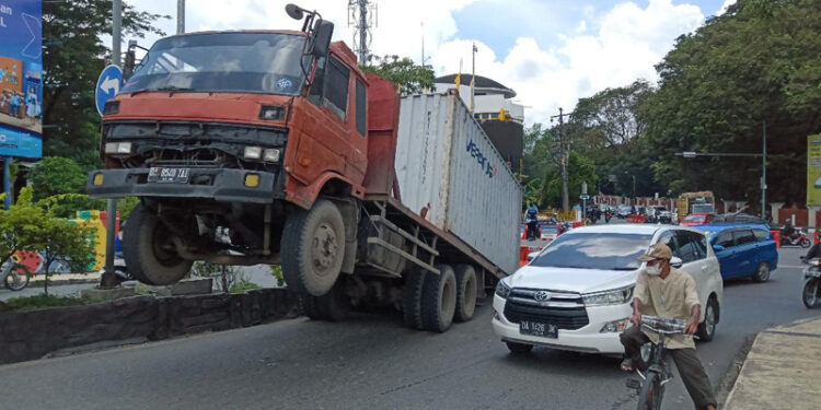 TERJUNGKIT - Sebuah mobil kontiner terjungkit di oprit Jembatan Merdeka, Senin (26/2) sekitar pukul 11.00 Wita. Kecelakaan tunggal itu pun sempat membuat arus lalu lintas menjadi terganggu.