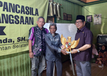 ANGGOTA DPRD Kalsel Dr H Karlie Hanafi Kalianda SH MH saat menyerahkan cinderamata berupa lambang negara saat sosialisasi di Kelurahan Ulu Benteng, Kecamatan Marabahan, Kabupaten Batola.