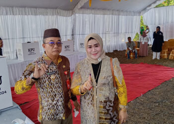 PJ Bupati Tapin M Syarifuddin MPd bersama istri saat usai mencoblos di TPS 11 dan memperlihatkan tanda tinta, Rabu (14/2).