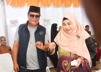 GUBERNUR Kalimantan Selatan H Sahbirin Noor bersama istrinya Hj Raudatul Jannah berfoto usai mencoblos di TPS 01 Keramat.