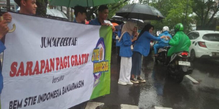 BAGI NASI BUNGKUS - Baksos, puluhan  mahasiswa dan mahasiswi STIE Indonesia Banjarmasin berbagi nasi bungkus di jalan raya dan sembako di Panti Asuhan Yayasan Insanul Kamil (Yainkam), Jumat (1/3).