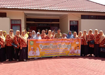 KETUA DWP Tapin Hj Mashuriyah berfoto bersama Camat Piani Arie Wijaya dan muspika kecamatan saat menyerahkan bantuan sembako untuk masyarakat tidak mampu, Senin (25/3).