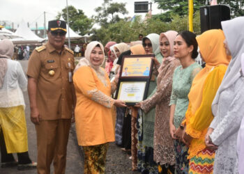 Ketua Tim Penggerak PKK Provinsi Kalimantan Selatan, Hj Raudatul Jannah, SKM, MKes atau Acil Odah didampingi Gubernur Kalsel, H Sahbirin Noor saat menyerahkan kepada perempuan berjasa dan berprestasi di banua.