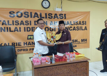 ANGGGOTA DPRD Dr H Karlie Hanafi Kalianda SH MH saat menyerahkan cinderamata berupa Lambang Negara Indonesia kepada Kepala BP2RD Kabupaten Batola Dahtiar Fajar.