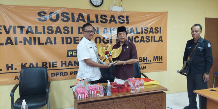 ANGGGOTA DPRD Dr H Karlie Hanafi Kalianda SH MH saat menyerahkan cinderamata berupa Lambang Negara Indonesia kepada Kepala BP2RD Kabupaten Batola Dahtiar Fajar.