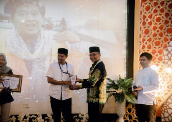Staf Ahli Gubernur Bidang Pemerintahan, Hukum dan Politik, Adi Santoso, SSos, MSi saat menyerahkan penghargaan pada Anugerah Syiar Ramadhan 2024, Lecture Theatre Gedung Kampus Baru Fisipol ULM Banjarmasin 