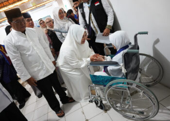 SAPA JEMAAH - Gubernur Kalimantan Selatan H Sahbirin Noor dan Ketua Tim Penggerak PKK Provinsi Kalsel Hj Raudatul Jannah atau Acil Odah menyapa calon jemaah haji lansia yang menggunakan kursi roda dari kloter 1 Embarkasi Banjarmasin.