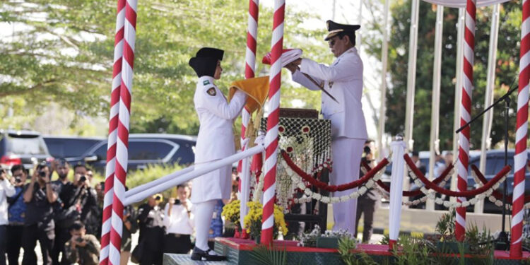 Gubernur Kalimantan Selatan, H Sahbirin Noor saat menyerahkan bendera merah putih pada salah satu anggota Paskibra pada penaikan bendera merah putih di HUT ke-79 Kemerdekaan RI