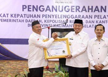 PJ Bupati Tapin M Syarifuddin saat menerima penghargaan dari Ombudsman RI Perwakilan Kalsel yang diserahkan Plt Gubernur Kalsel H Muhidin di Swiss Bel Hotel Banjarmasin, Rabu (11/12).