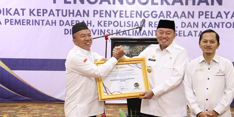 PJ Bupati Tapin M Syarifuddin saat menerima penghargaan dari Ombudsman RI Perwakilan Kalsel yang diserahkan Plt Gubernur Kalsel H Muhidin di Swiss Bel Hotel Banjarmasin, Rabu (11/12).