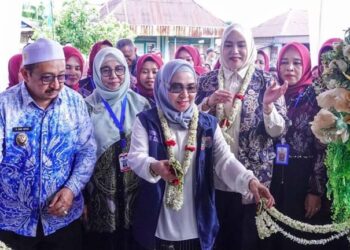 Ketua Tim Pembina (TP) Posyandu Provinsi Kalimantan Selatan, Hj Fathul Jannah Muhidin saat memotong untaian melati pada Posyandu Jati 2, Desa Pasar Jati, Kabupaten Banjar