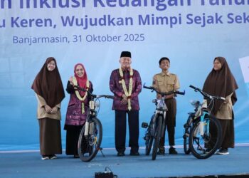 Gubernur Kalimantan Selatan, H Muhidin didampingi isteri, Hj Fathul Jannah berfoto bersama siswa Ukhuwah Banjarmasin yang menerima hadiah sepeda pada puncak Bulan Inklusi Keuangan Tahun 2025, di Gedung Ukhuwah Banjarmasin