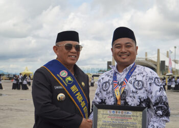 BUPATI Kotabaru H Muhammad Rusli berfoto bersama salah satu penerima penghargaan usai upacara peringatan HUT PGRI dan HGN Tahun 2025 di Lapangan Siring Laut Kotabaru, Senin (8/12) pagi.