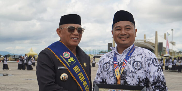 BUPATI Kotabaru H Muhammad Rusli berfoto bersama salah satu penerima penghargaan usai upacara peringatan HUT PGRI dan HGN Tahun 2025 di Lapangan Siring Laut Kotabaru, Senin (8/12) pagi.