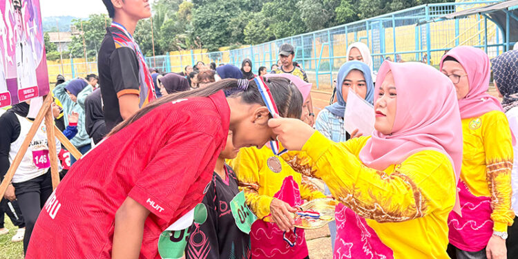 PENASIHAT Perwosi Kotabaru Suci Anisa Rusli saat mengalungkan medali kepada salah satu pemenang Kejuaraan Atletik Wanita Tingkat SMP/SMA Sederajat dan Perguruan Tinggi di Lapangan Stadion Bamega, Minggu (14/12).