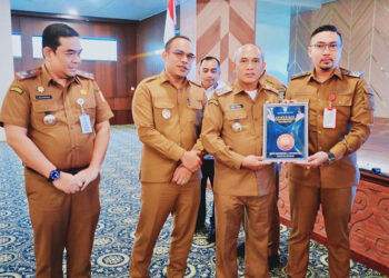 BUPATI Kotabaru H Muhammad Rusli didampingi Wabup Syairi Mukhlis saat menyerahkan piagam apresiasi kepada salah satu SKPD di Aula Bamega, Senin (5/1).