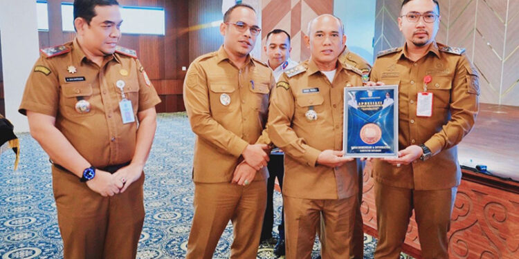 BUPATI Kotabaru H Muhammad Rusli didampingi Wabup Syairi Mukhlis saat menyerahkan piagam apresiasi kepada salah satu SKPD di Aula Bamega, Senin (5/1).