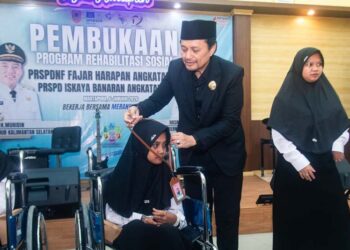 Wakil Gubernur (Wagub) Kalimantan Selatan, H Hasnuryadi Sulaiman ketika mengalungkan tanda peserta pada salah satu peserta rehabilitasi bagi penyandang disabilitas di Kalsel