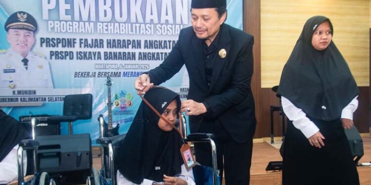 Wakil Gubernur (Wagub) Kalimantan Selatan, H Hasnuryadi Sulaiman ketika mengalungkan tanda peserta pada salah satu peserta rehabilitasi bagi penyandang disabilitas di Kalsel
