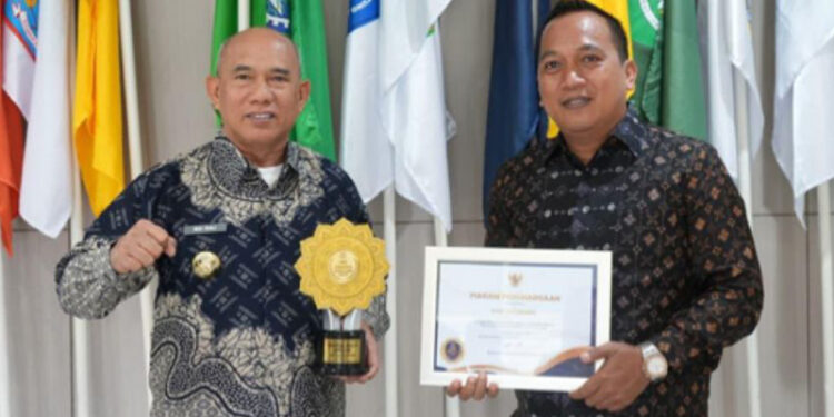 SEKDA Kotabaru Eka Saprudin saat menyerahkan penghargaan UHC Award 2026 Kategori Madya kepada Bupati Kotabaru Muhammad Rusli, Rabu (28/1).