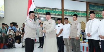 Gubernur Kalimantan Selatan, H Muhidin saat menyerahkan bendera Mrah Putih kepada pimpinan rombongan Kloter 1 Embarkasi Haji Banjarmasin sebagai tanda dilepasnya calon jemaah haji (CJH) asal Kalsel di Asrama Haji Banjarmasin, di Banjarbaru