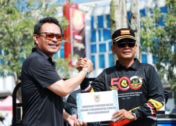 Plh Sekdaprov Kalimantan Selatan, H Subhan Nor Yaumil saat menyerahkan bantuan fasilitas pengelolaan sampah dan diterima Walikota Banjarmasin, HM Yamin HR disela aksi bersih-bersih dalam rangka peringatan Hari Lingkungan Hidup Sedunia tahun 2026